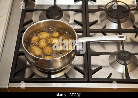 Pan of potato's boiling on a gas stove hob. Stock Photo