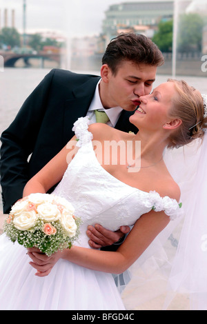 Young newlywed couple kissing outdoors with river in background urban scene. Stock Photo