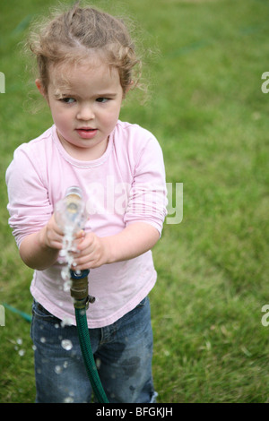 Little girl holding a garden hose Stock Photo