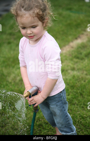 Little girl holding a garden hose Stock Photo