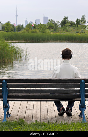 Man sitting on park bench wearing headphones, Toronto, Ontario Stock Photo