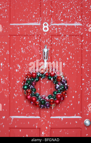 Christmas wreath hanging on door, with snowfall Stock Photo