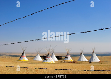 Indian teepees on prairie and barbed wire fence at Head Smashed in Buffalo Jump interpretive centre, Alberta, Canada Stock Photo