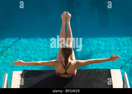 Female swimmer sitting on diving board Stock Photo