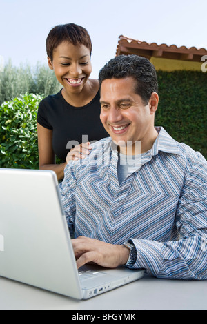 Couple using laptop in back yard Stock Photo