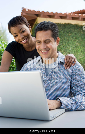 Couple using laptop in back yard Stock Photo
