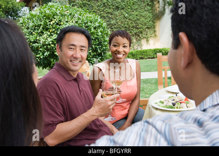 Two couples drinking wine in garden Stock Photo