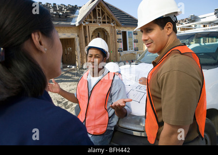 Architect and two construction workers having discussion on construction site Stock Photo