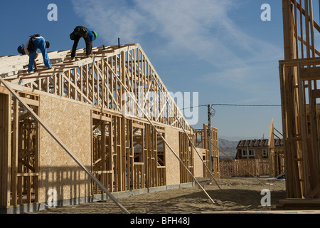 Two construction workers working on roof of half constructed house Stock Photo