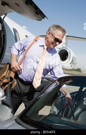 Senior businessman getting of airplane and getting in car. Stock Photo