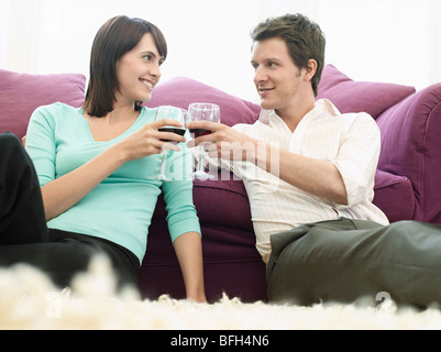 Young couple relaxing on sofa, toasting with wine Stock Photo