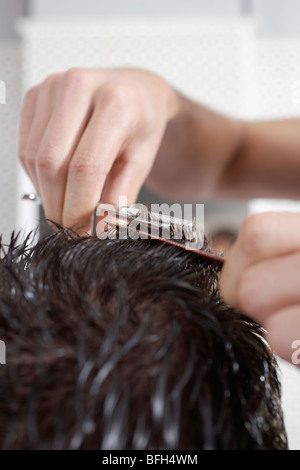 Barber cutting mans hair in barber shop, close-up Stock Photo