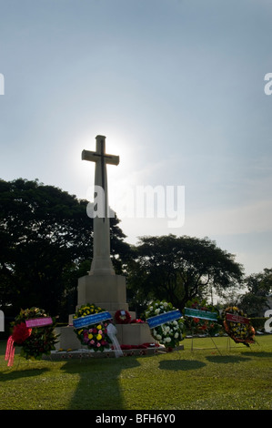 Floral offerings at the foot of the cross of Kanchanaburi War Cemetery in Thailand Stock Photo