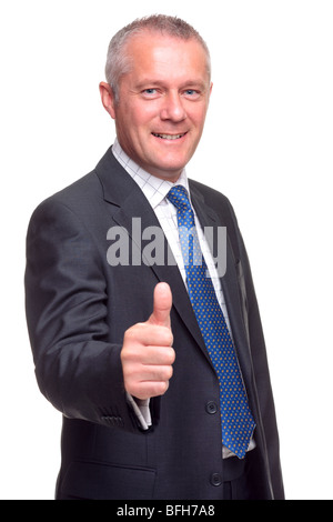 Mature businessman in suit and tie giving a thumbs up gesture towards camera, isolated on a white background. Stock Photo
