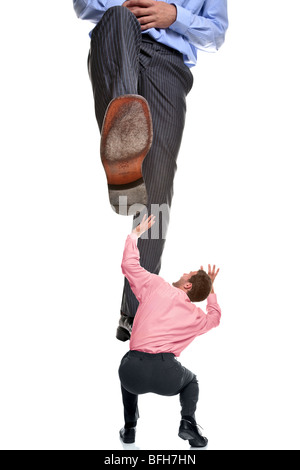 A businessman about to be stepped on by a giant foot, isolated on a white background. Stock Photo