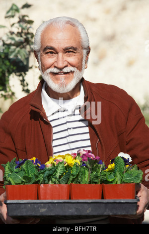 Elderly man holding tray with potted flowers Stock Photo