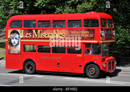 Side view red double decker classic iconic Routemaster London bus  advertising poster for famous Les Misérables musical at Queens Theatre England UK