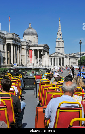 Passengers on open top tour bus approaching Trafalgar Square Stock Photo