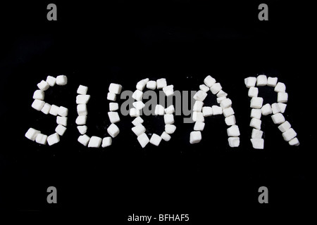 Sugar written in sugar lumps on a black studio background. Stock Photo