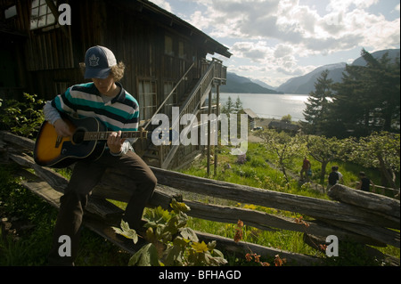 A young man plays his guitar  at the well known Strathcona Park Lodge, British Columbia, Canada. Stock Photo