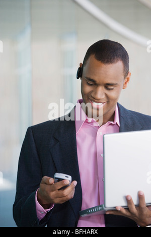 Mid adult man using laptop and PDA outdoors Stock Photo