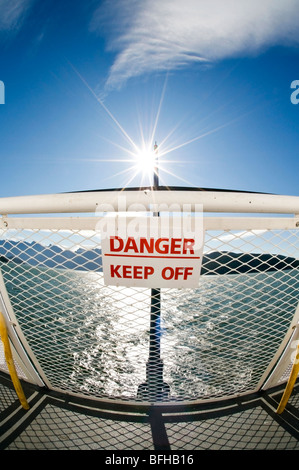 A sign on a ferry railing states 'Danger - Keep Off'. Stock Photo