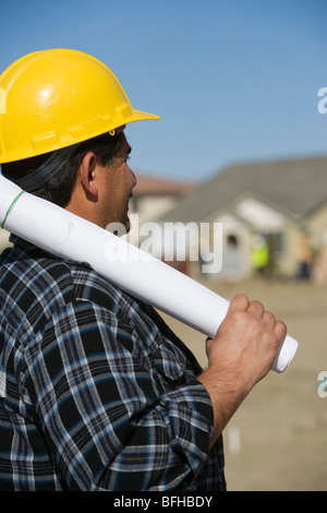 Man holding rolled up blueprint in construction site Stock Photo - Alamy