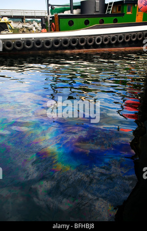 An Oil slick sits on the surface of the water in a marina. Stock Photo