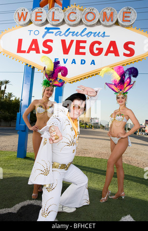 Female dancers and Elvis impersonator posing in front of Las Vegas welcome sign, Nevada, USA Stock Photo