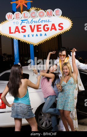 Young woman photographing two friends with Elvis impersonator Welcome to fabulous Las Vegas sign in background, Nevada, USA Stock Photo