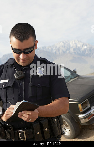 Police officer taking notes in front of car Stock Photo