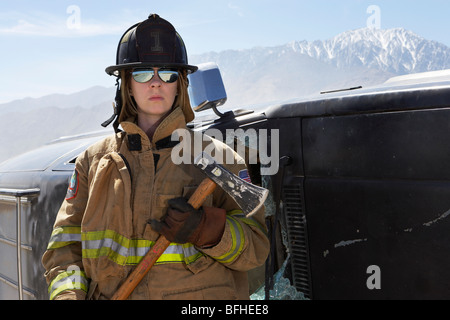 Portrait of female firefighter holding axe in mountains Stock Photo