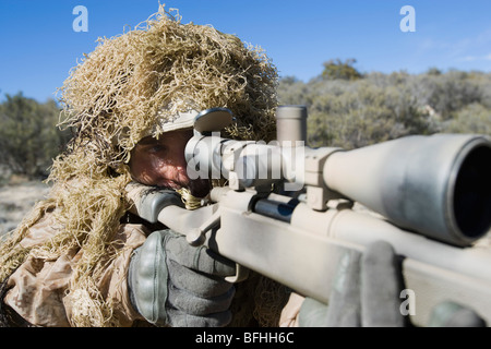 Soldier in grass camouflage pointing rifle Stock Photo