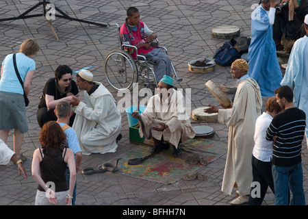 Tourists intermingle with snake charmers on Djemaa el-Fna, the central square in Marrakesh, now a UNESCO World Heritage Site Stock Photo