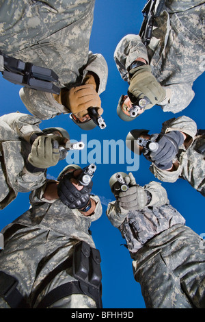 Low angle portrait of soldiers standing in circle, aiming Stock Photo