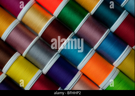 Bright colored spools of thread in rows Stock Photo