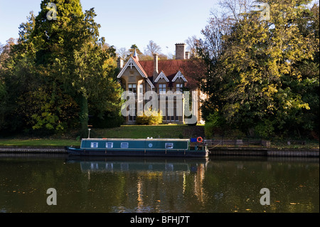 A narrow boat moored outside a large house on the banks of the River Thames at Maidenhead Berkshire UK Stock Photo