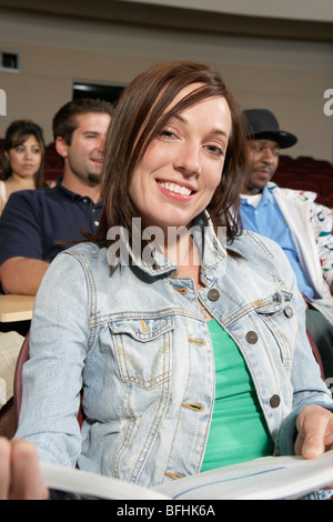 Portrait of female college student in classroom, others in classroom Stock Photo
