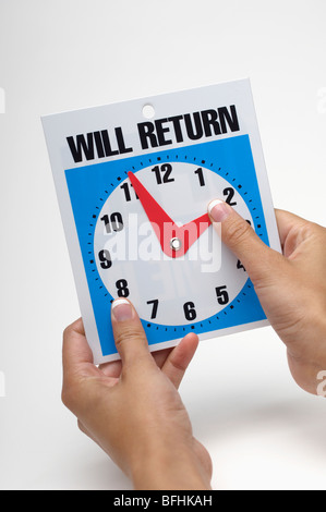 Woman adjusting hands of Will return clock, close-up Stock Photo