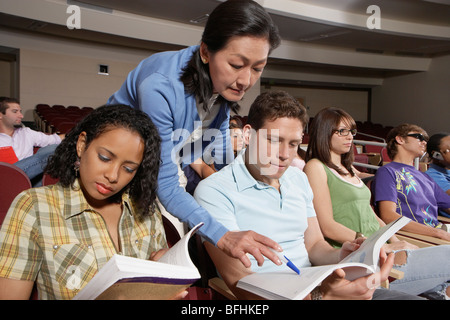 Female teacher assisting students during lesson Stock Photo