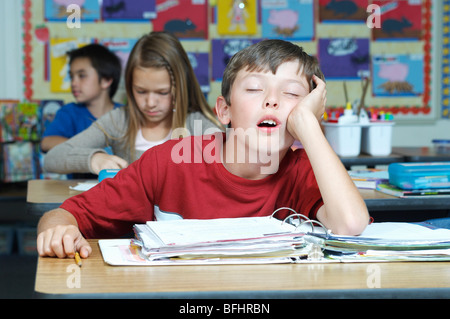 Three pupils in classroom, one of them sleeping Stock Photo