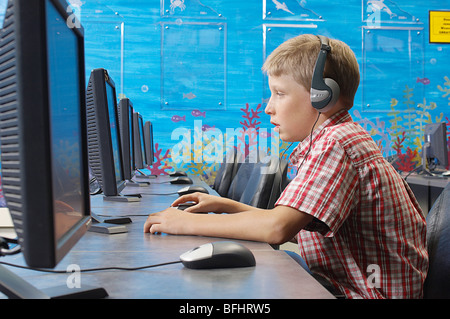 School boy wearing headphones in computer room Stock Photo