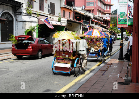 Man pedalling colourful trishaws in Melaka West Malaysia Stock Photo