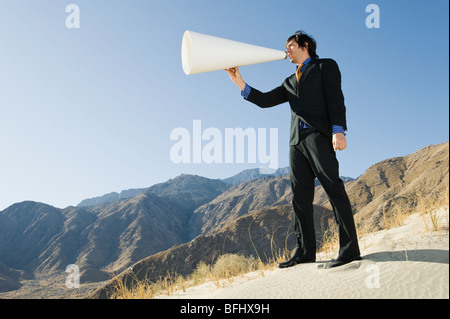 Businessman Using Megaphone in Desert Stock Photo