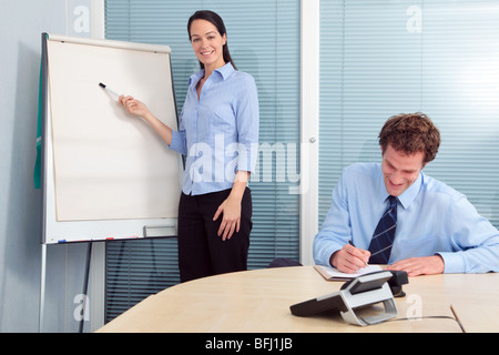 Businesswoman giving a presentation, blank flip chart to add your own text. Stock Photo