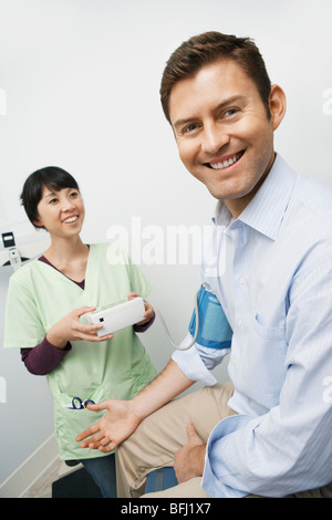 Doctor checking male patients blood pressure in hospital Stock Photo