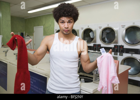 Young man washing clothes at launderette Stock Photo