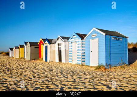 The famous colourful Southwold Beach huts against a bright vibrant blue sky on the Suffolk Coast Stock Photo