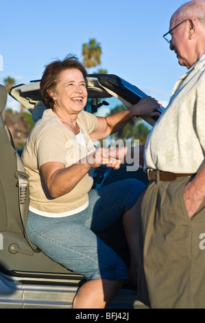 Senior woman getting out of car, senior man holding womans hand Stock Photo