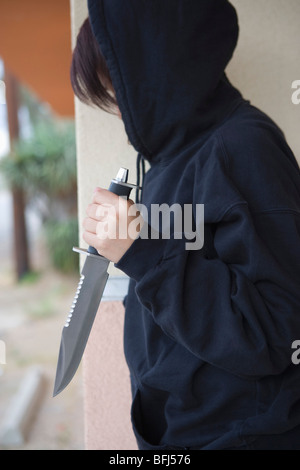 Robber with knife hiding behind corner Stock Photo